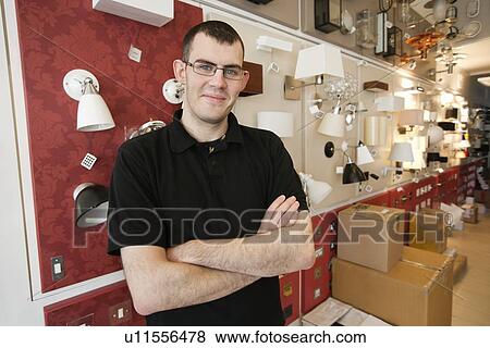 Stock Photo - Portrait of a young male standing with arms crossed in store. Fotosearch