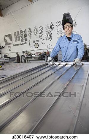 Portrait of a young metalworker wearing welding mask in workshop View Large Photo Image Stock Photo - Portrait of a young metalworker wearing welding mask in workshop. Fotosearch