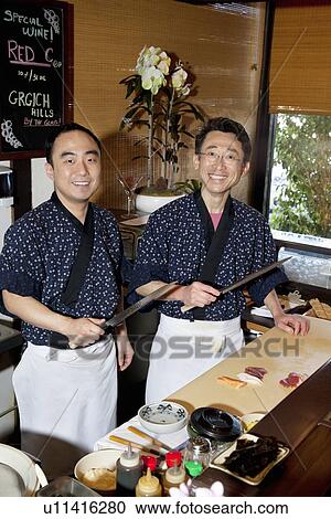 Stock Image - Portrait of Asian chefs preparing sushi together. Fotosearch