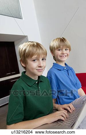 Picture - Portrait of blond brothers using laptop. Fotosearch