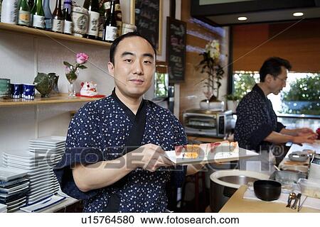 Portrait of chef holding sushi tray with coworker in background View Large Photo Image Stock Image - Portrait of chef holding sushi tray with coworker in background. Fotosearch