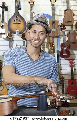 Portrait of happy man restringing guitar in music store View Large Photo Image Stock Photo - Portrait of happy man restringing guitar in music store. Fotosearch