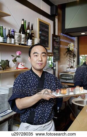 Stock Photography - Portrait of mature chef with Japanese cuisine. Fotosearch