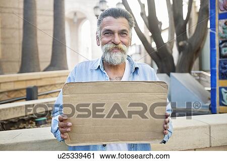 Stock Image - Portrait of smiling homeless person with sign. Fotosearch