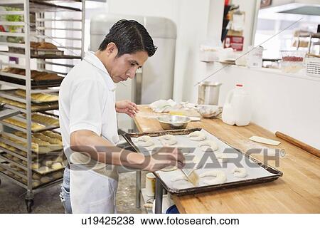 Side view of a young male baker making dough in bakery View Large Photo Image Stock Photo - Side view of a young male baker making dough in bakery. Fotosearch