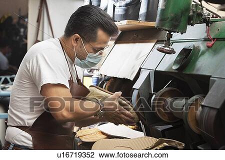 Stock Image - Skilled cobbler polishing show sole in machinery. Fotosearch