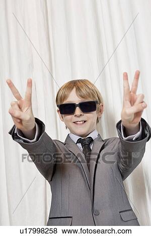 Stock Photo - Young boy wearing sunglasses gesturing peace sign. Fotosearch