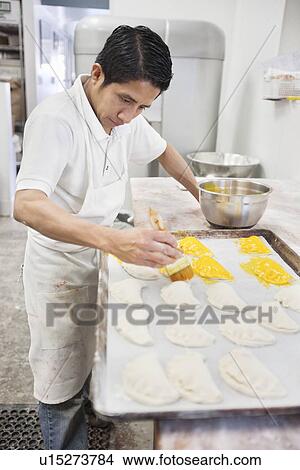 Young male baker working on preparation of pastry in bakery kitchen View Large Photo Image Picture - Young male baker working on preparation of pastry in bakery kitchen. Fotosearch