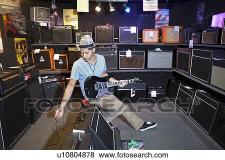 Young male customer plugging electric guitar to speaker View Large Photo Image Stock Photo - Young male customer plugging electric guitar to speaker. Fotosearch