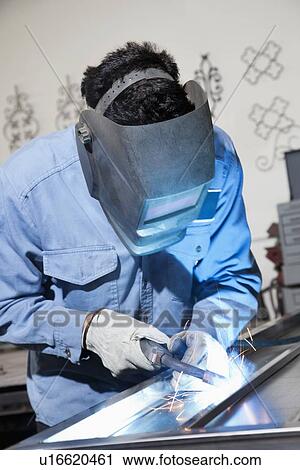 Young man wearing welding mask while working in metal workshop View Large Photo Image Stock Image - Young man wearing welding mask while working in metal workshop. Fotosearch