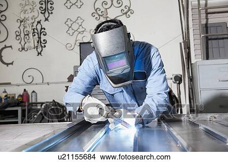 Picture - Young man welding in metal workshop. Fotosearch
