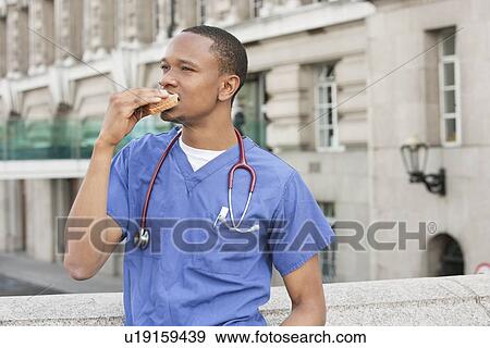 African American male doctor eating sandwich with building in background View Large Photo Image Stock Photo - African American male doctor eating sandwich with building in background. Fotosearch