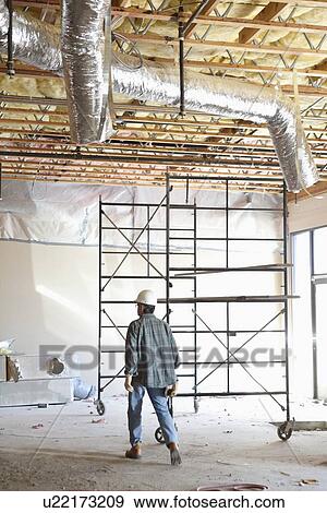 Back view of contractor walking at construction site View Large Photo Image Stock Photo - Back view of contractor walking at construction site. Fotosearch