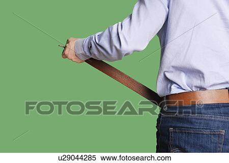 Stock Photography - Back view of man's torso adjusting belt over colored background. Fotosearch