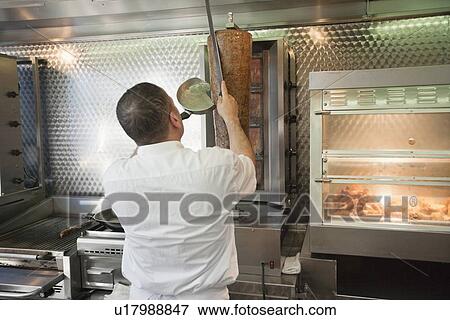 Stock Photo - Back view of mid adult man working in fast food shop. Fotosearch
