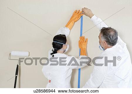 Picture - Back view of two manual workers doing preparation to paint room. Fotosearch