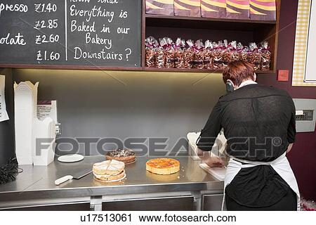 Back view of young attendant working in bakery store View Large Photo Image Stock Image - Back view of young attendant working in bakery store. Fotosearch