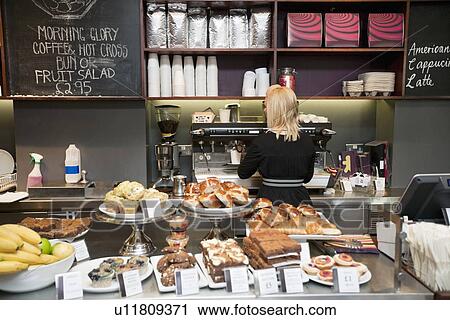 Back view of young woman working in bakery shop with pastries on display View Large Photo Image Stock Image - Back view of young woman working in bakery shop with pastries on display. Fotosearch