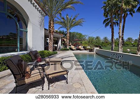 Stock Image - Chaise lounges at poolside in luxury villa. Fotosearch