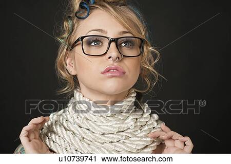 Close-up of beautiful young woman wearing retro glasses with rope around neck looking away over colored background View Large Photo Image Stock Image - Close-up of beautiful young woman wearing retro glasses with rope around neck looking away over colored background. Fotosearch