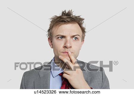 Stock Photograph - Close-up of young businessman thinking hard over colored background. Fotosearch