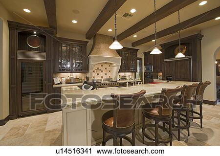 Stock Image - Contemporary kitchen counter with chair in luxury mansion. Fotosearch