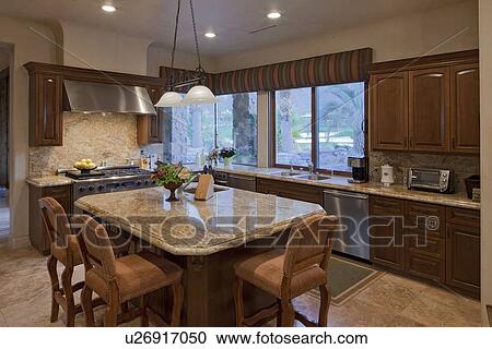 Stock Image - Contemporary kitchen counter with chair in luxury villa. Fotosearch