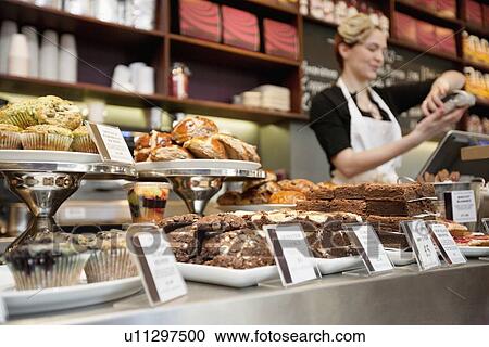 Stock Image - Fresh pastries displayed with young woman attendant in background. Fotosearch