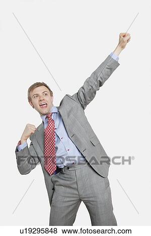 Stock Photo - Handsome young businessman with clenched fist over colored background. Fotosearch