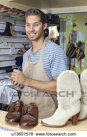 Handsome young shoemaker with handmade shoes and boots writing View Large Photo Image Stock Photo - Handsome young shoemaker with handmade shoes and boots writing. Fotosearch