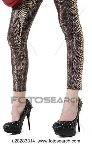 Picture - Low section of female legs with high heels over white background. Fotosearch