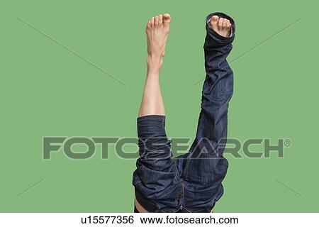 Low section of upside down man wearing jeans over colored background View Large Photo Image Stock Photograph - Low section of upside down man wearing jeans over colored background. Fotosearch