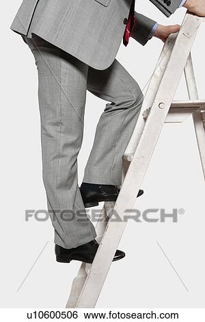 Stock Photograph - Low section view of a businessman climbing up a ladder. Fotosearch
