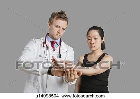Male doctor checking pulse rate of female patient View Large Photo Image Picture - Male doctor checking pulse rate of female patient. Fotosearch
