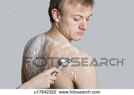 Man looking at hand shaving his back over colored background View Large Photo Image Stock Image - Man looking at hand shaving his back over colored background. Fotosearch
