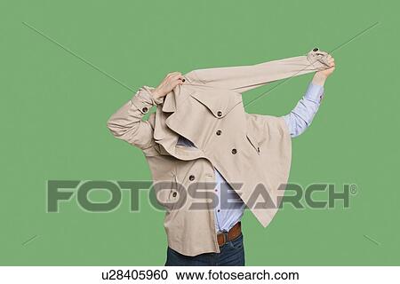 Man struggling to wear jacket over colored background View Large Photo Image Stock Image - Man struggling to wear jacket over colored background. Fotosearch