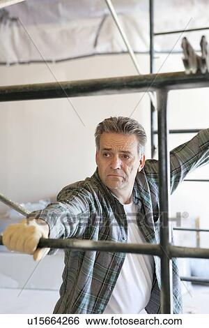 Mature contractor standing near scaffolding View Large Photo Image Stock Photograph - Mature contractor standing near scaffolding. Fotosearch