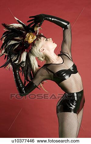 Stock Photograph - Pinup woman in fishnet stockings and leather posing over colored background. Fotosearch