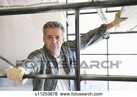 Portrait of a contractor standing near scaffolding View Large Photo Image Stock Photo - Portrait of a contractor standing near scaffolding. Fotosearch