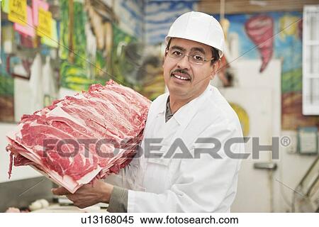 Stock Photography - Portrait of butcher holding meat tray in store. Fotosearch
