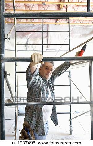 Portrait of contractor with drill standing under scaffolding View Large Photo Image Stock Photo - Portrait of contractor with drill standing under scaffolding. Fotosearch