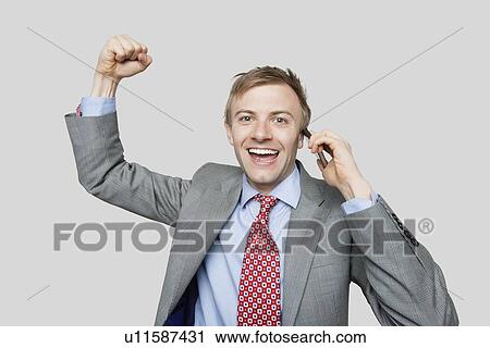 Portrait of handsome businessman with clenched fist talking on cell phone over colored background View Large Photo Image Stock Image - Portrait of handsome businessman with clenched fist talking on cell phone over colored background. Fotosearch