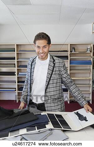 Portrait of handsome young man choosing fabric for making suit in tailor's shop View Large Photo Image Picture - Portrait of handsome young man choosing fabric for making suit in tailor's shop. Fotosearch