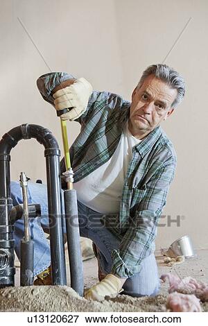 Portrait of mature man measuring pipe at construction site View Large Photo Image Stock Photo - Portrait of mature man measuring pipe at construction site. Fotosearch
