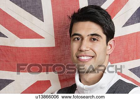 Stock Photograph - Portrait of patriotic young man with British flag in background. Fotosearch