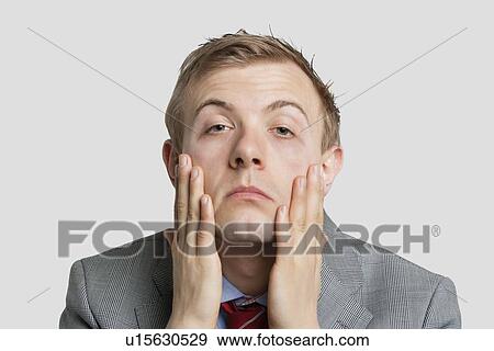 Portrait of tired young businessman over light gray background View Large Photo Image Stock Photo - Portrait of tired young businessman over light gray background. Fotosearch