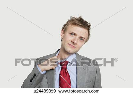 Portrait of young businessman loosening tie over colored background View Large Photo Image Stock Photo - Portrait of young businessman loosening tie over colored background. Fotosearch