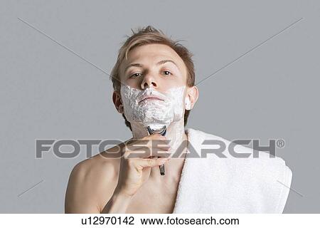 Portrait of young man grooming himself over colored background View Large Photo Image Stock Image - Portrait of young man grooming himself over colored background. Fotosearch