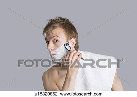 Portrait of young man shaving over colored background View Large Photo Image Stock Image - Portrait of young man shaving over colored background. Fotosearch
