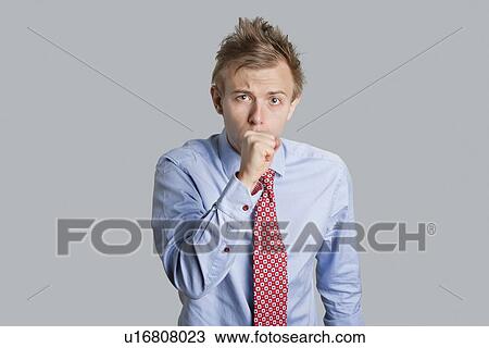 Portrait of young man with hand covering mouth while coughing over colored background View Large Photo Image Stock Image - Portrait of young man with hand covering mouth while coughing over colored background. Fotosearch